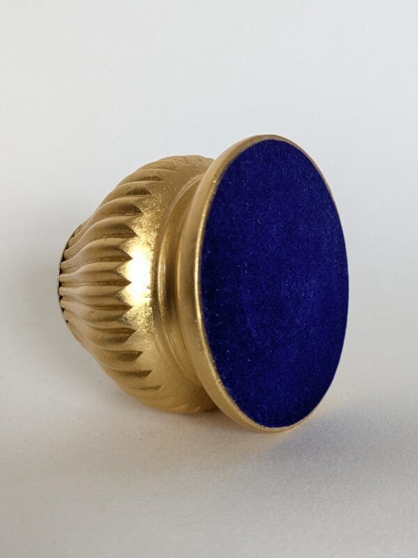 View of the underside of gold candle holder showing blue flocked base