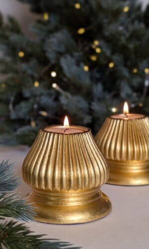 gold fluted candle holders in front of christmas tree with lights