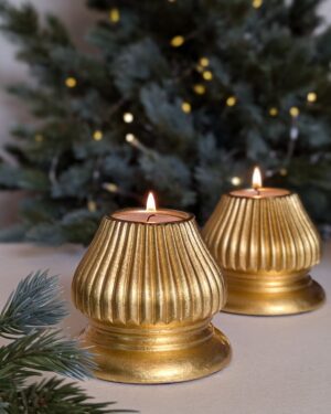 gold fluted candle holders in front of christmas tree with lights