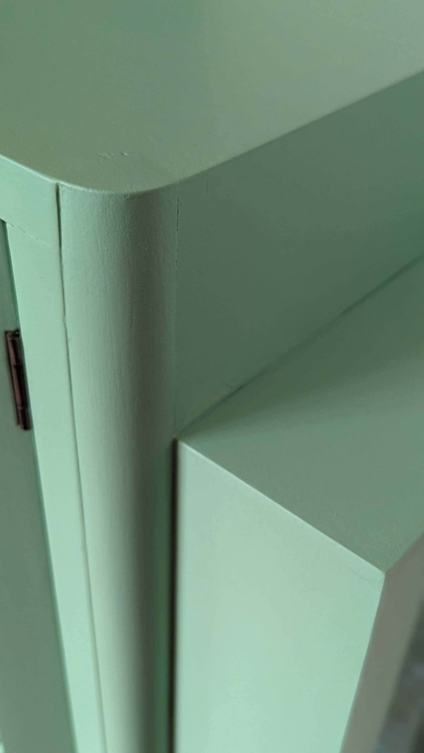 Top corner of pistachio green hand painted vintage display cabinet