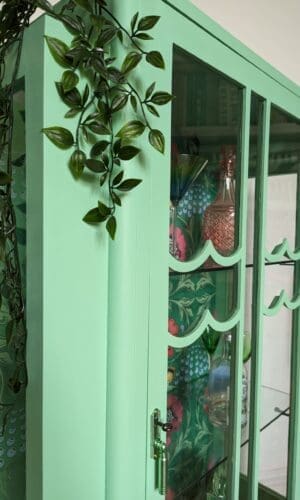 Scalloped glass panels to front of vintage green hand painted cabinet