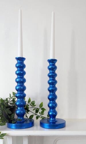 Metallic royal blue bobbin candlesticks on mantlepiece with trailing plant