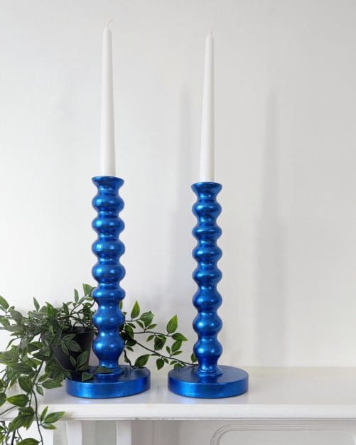 Metallic royal blue bobbin candlesticks on mantlepiece with trailing plant