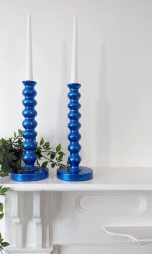 Metallic royal blue bobbin candlesticks on mantlepiece with trailing plant