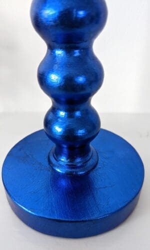 Close up of base of blue gilded bobbin candlestick showing soft metallic sheen and texture