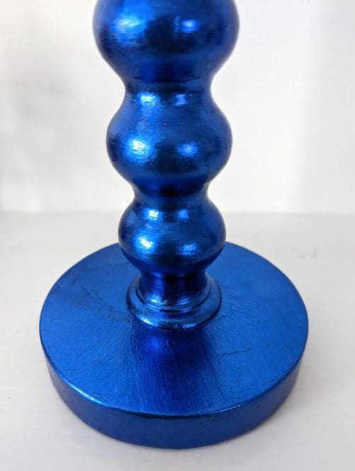 Close up of base of blue gilded bobbin candlestick showing soft metallic sheen and texture
