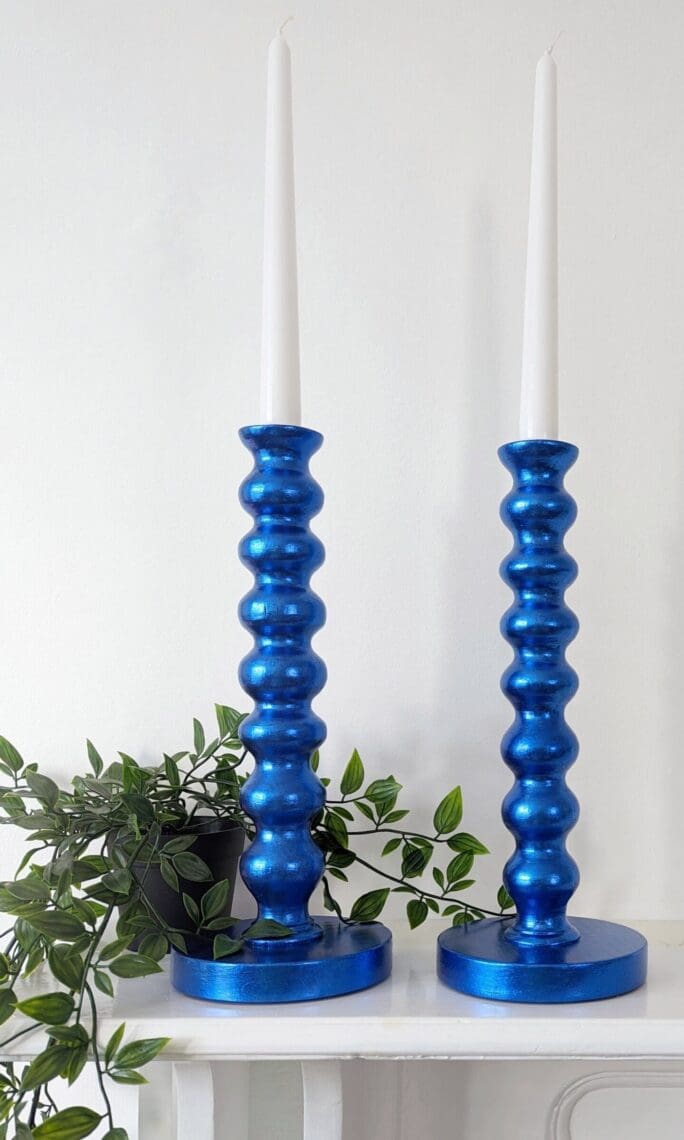Metallic royal blue bobbin candlesticks on mantlepiece with trailing plant