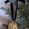 Gold walnut decoration with navy velvet bow hanging on a Christmas tree