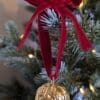 Gold walnut decoration with red velvet bow hanging on a Christmas tree