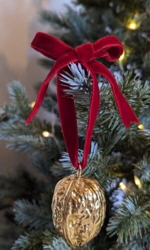 Gold walnut decoration with red velvet bow hanging on a Christmas tree