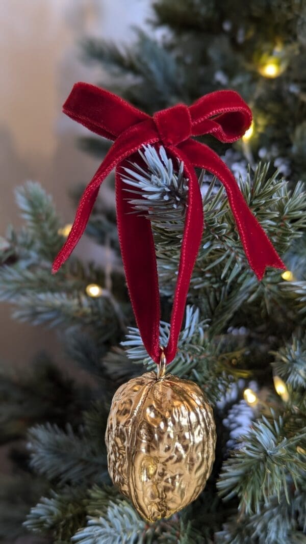 Gold walnut decoration with red velvet bow hanging on a Christmas tree