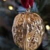 Real gold gilded walnut Christmas decoration hanging by a red velvet ribbon from a Christmas tree