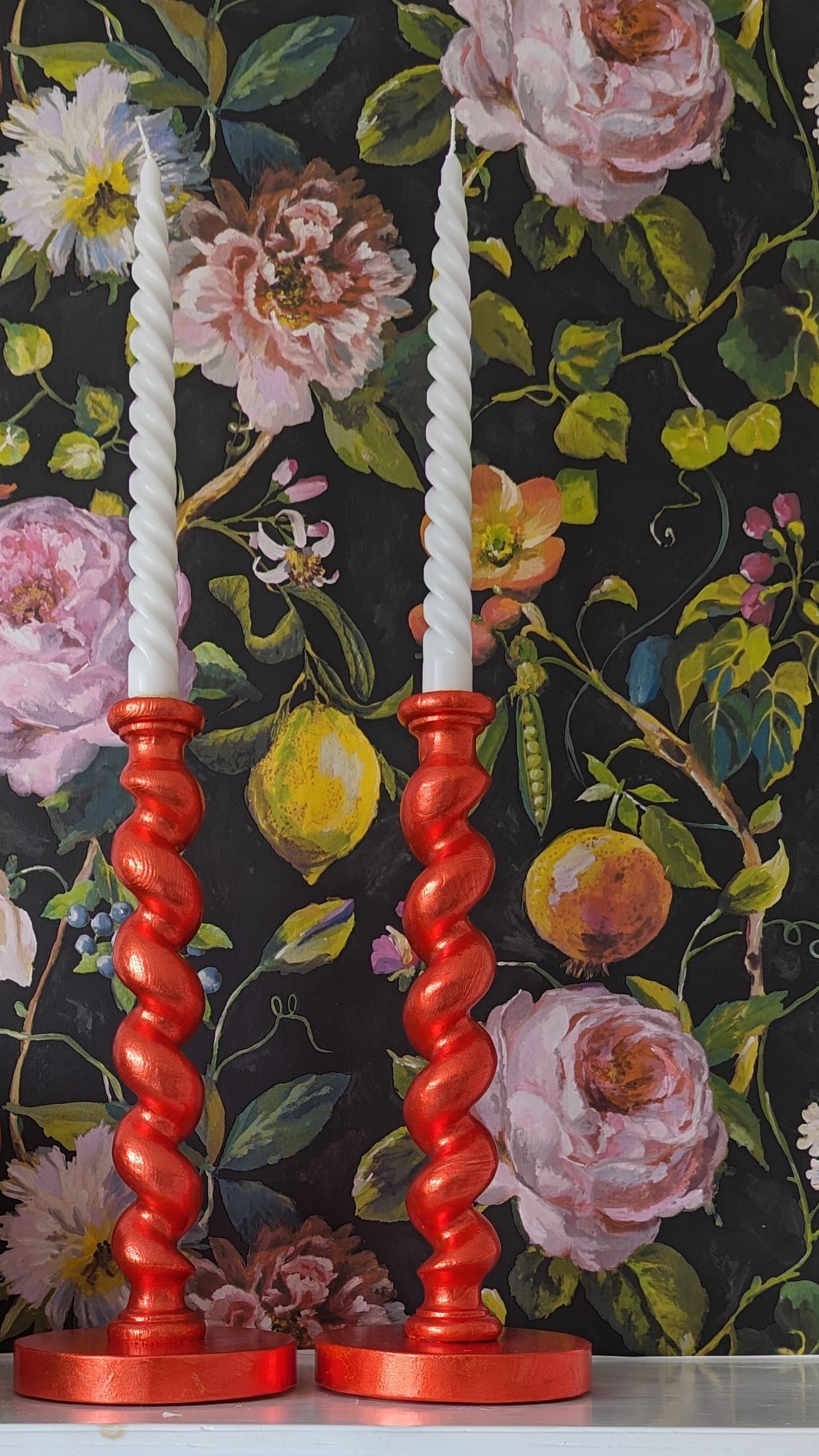 orange candlesticks against dark floral background