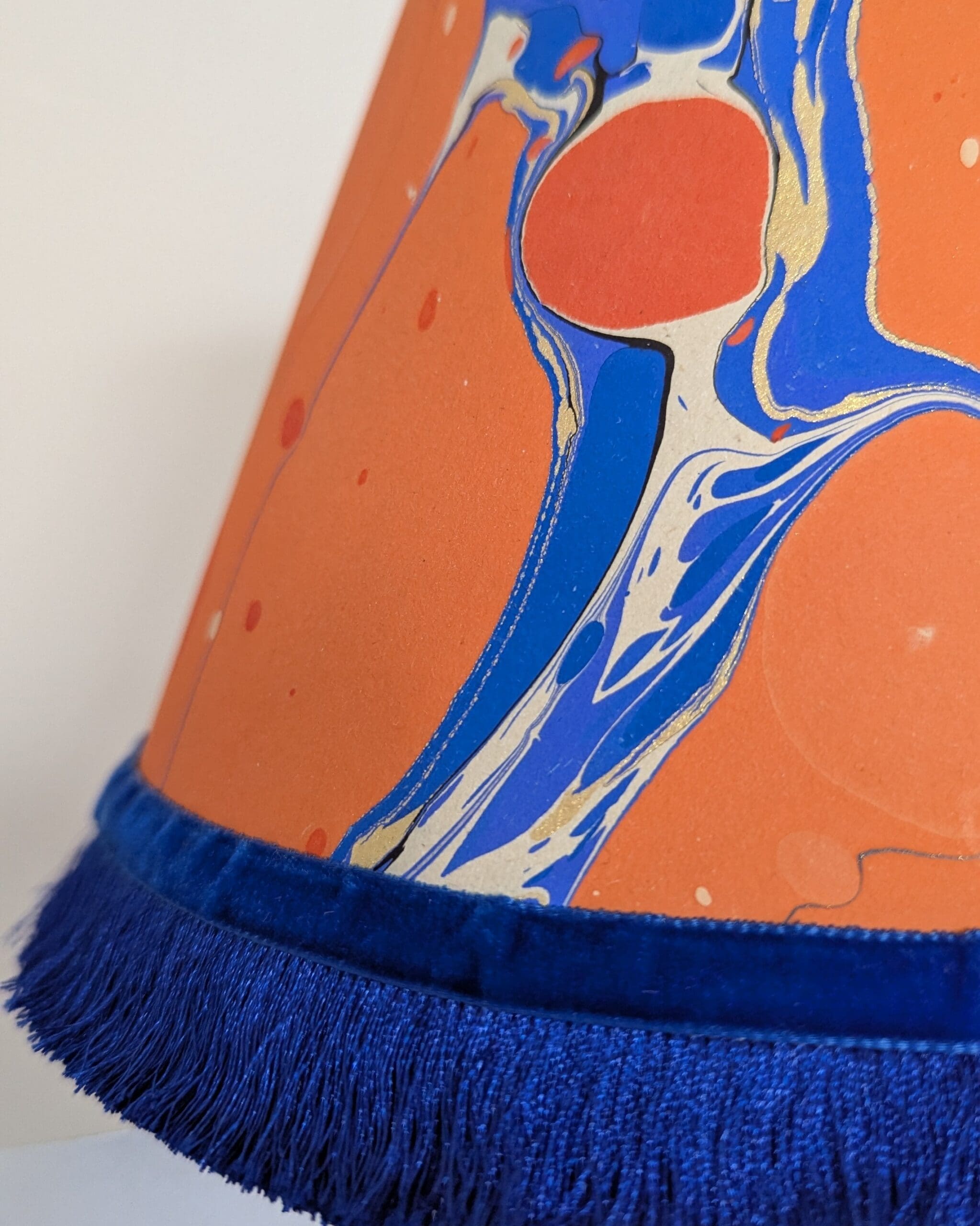 orange and blue marbled lampshade close up detail of royal blue silky fringing and velvet ribbob trim