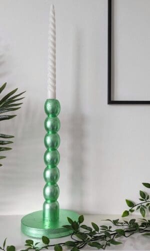Metallic mint green bobbin candlesticks on mantlepiece with trailing plant