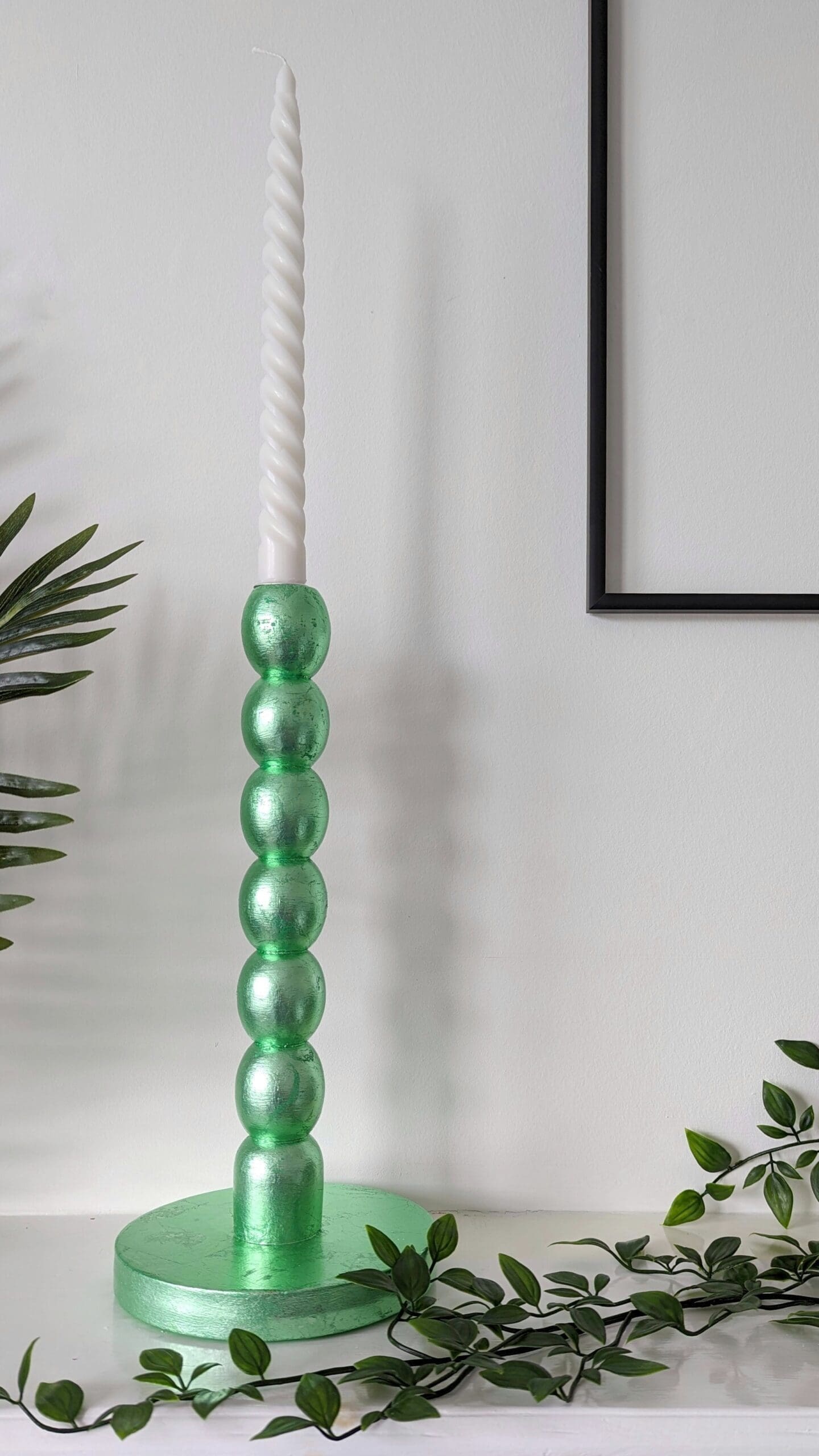 Metallic mint green bobbin candlesticks on mantlepiece with trailing plant