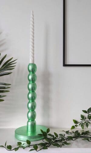 Metallic mint green bobbin candlesticks on mantlepiece with trailing plant
