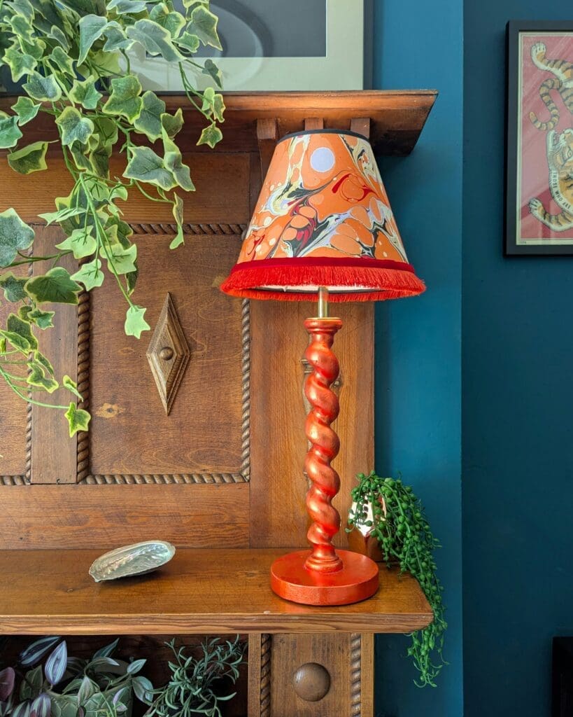orange twist lamp with marbled lampshade on wooden mantelpiece