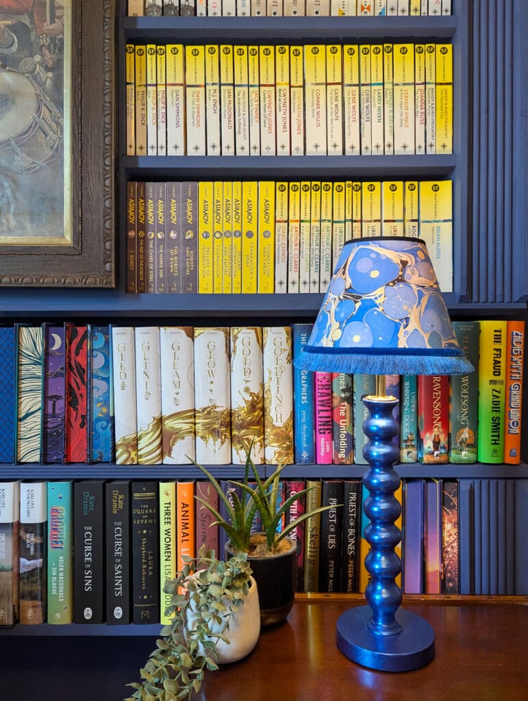 Blue cordless lamp on small table in blue library with colourful books