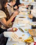 Close up of woman gilding a walnut with gold leaf wearing white cotton gloves