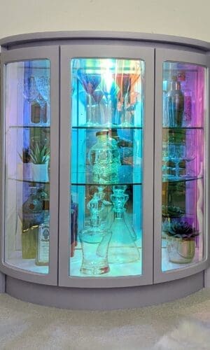 Iridescent glass drinks cabinet glowing in low light