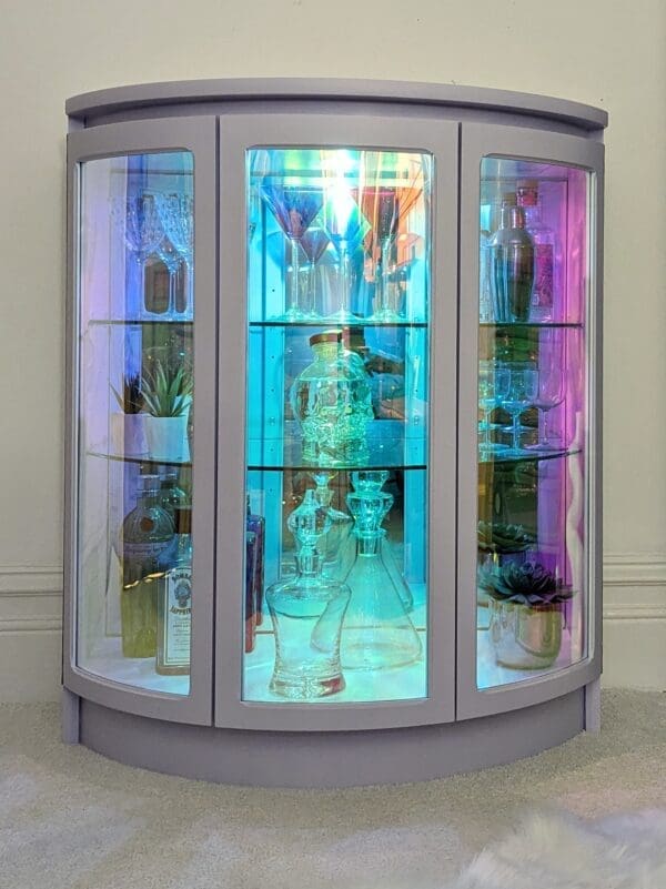 Iridescent glass drinks cabinet glowing in low light
