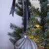 Grey and silver marbled Christmas bauble decoration hanging from dark grey ribbon on a Christmas tree