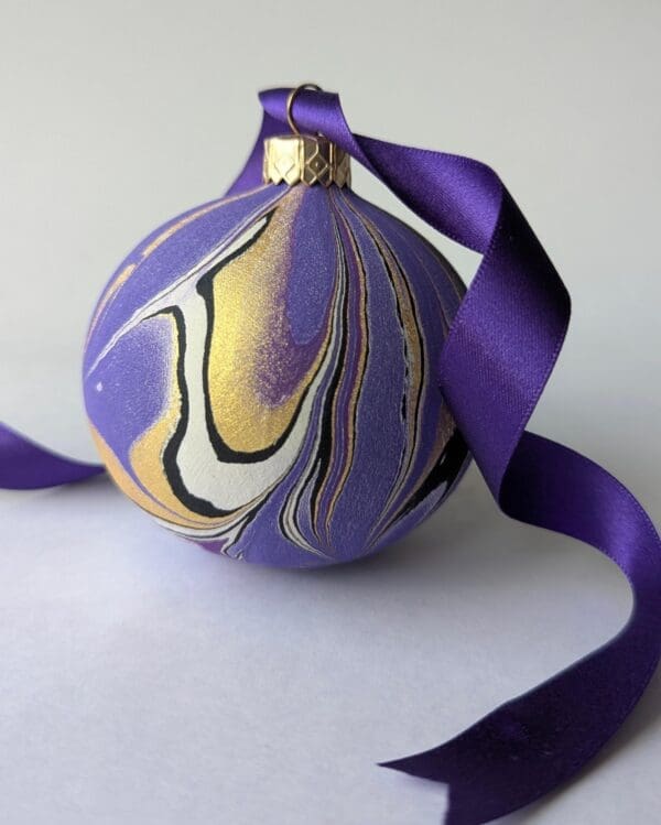 Purple and gold marbled bauble with trailing purple satine ribbon