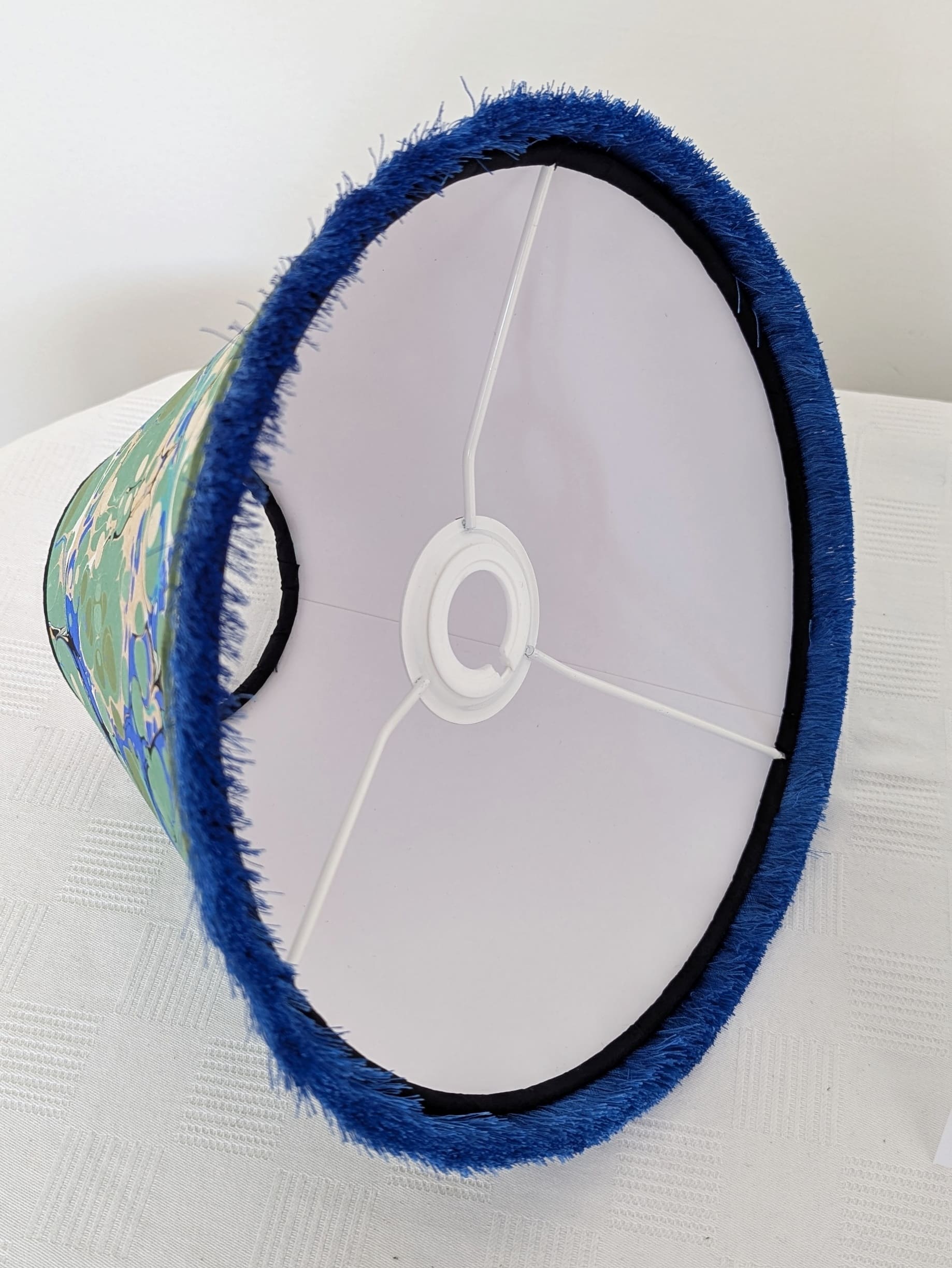Inside view of blue and green marbled lampshade showing white cardboard interior