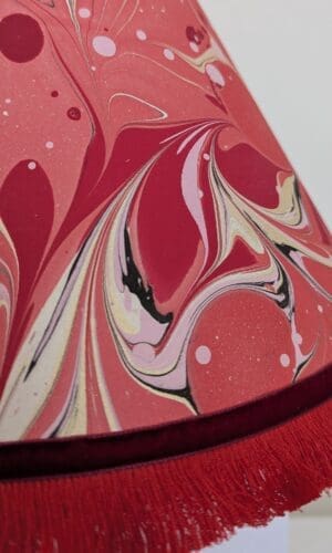 close up of red marbled lampshade showing red fringe trim