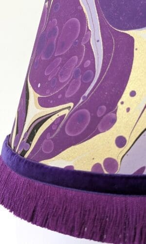 close up of purple and gold marbled lampshade with purple fringing and velvet ribbon trim