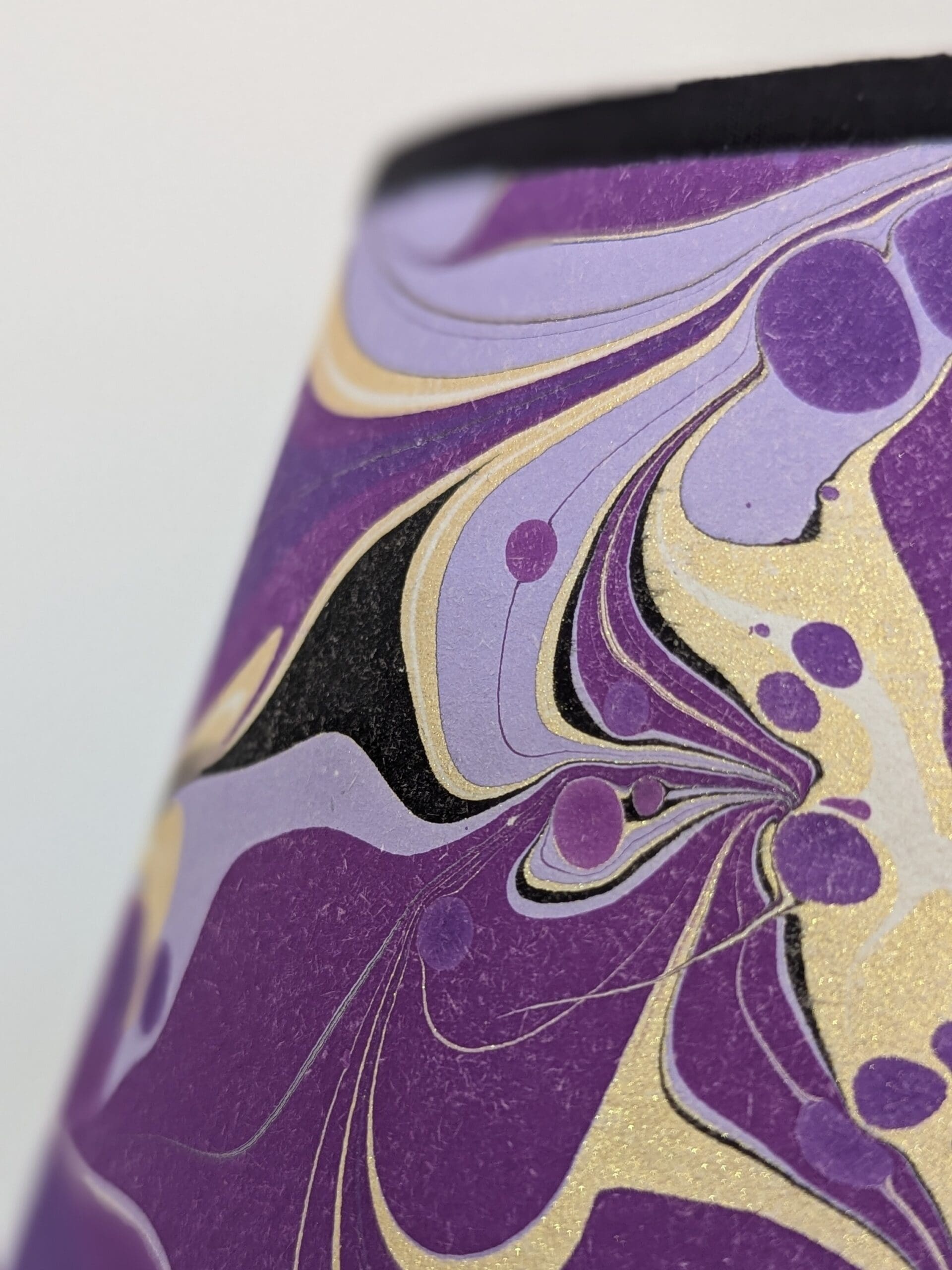 close up of swirling purple, lilac, gold and black pattern on handmade paper lampshade
