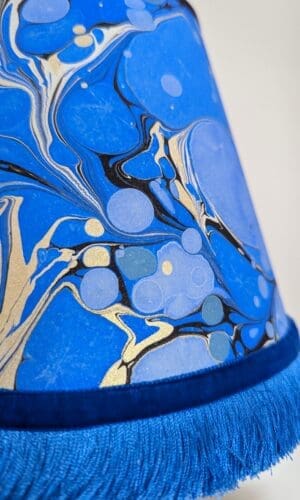 detail of blue and gold marbled paper lampshade with blue fringing and velvet ribbon trim