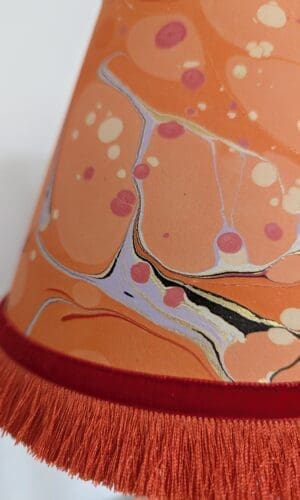 close up of orange marbled paper lampshade showing orange fringing