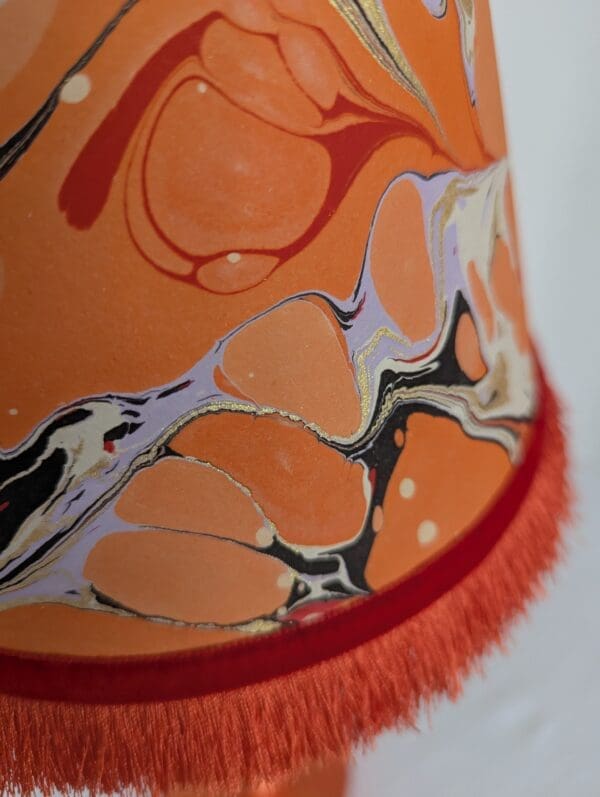 close up of orange, lilac, black and red marbled paper lampshade