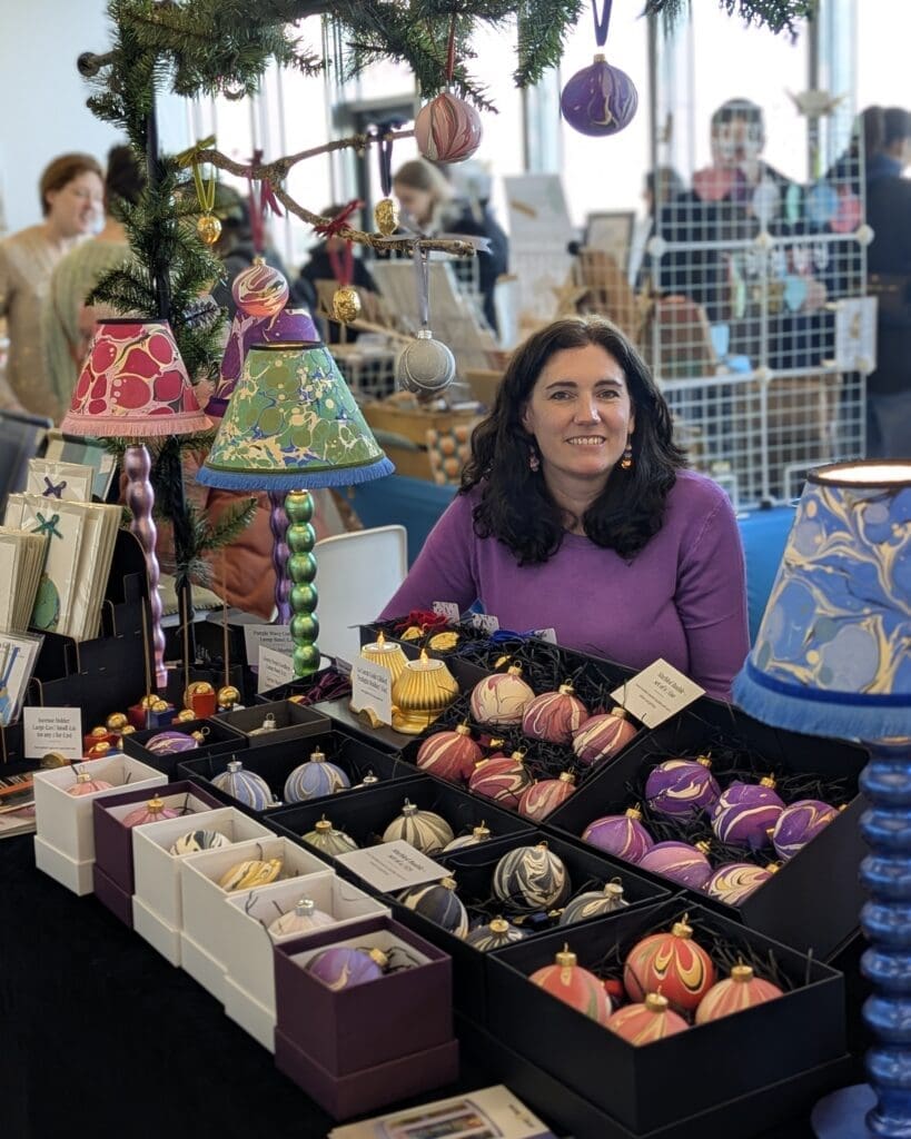 PXL_20251102_133906477.PORTRAIT Carrie Webb sitting at her stall at the Brighter Days market at the Turner Contemporary in Margate