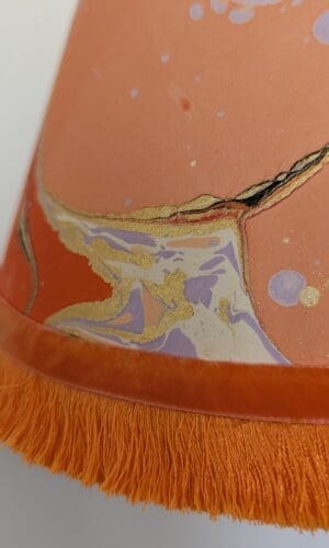 Peach marbled lampshade with bright orange trim and velvet ribbon