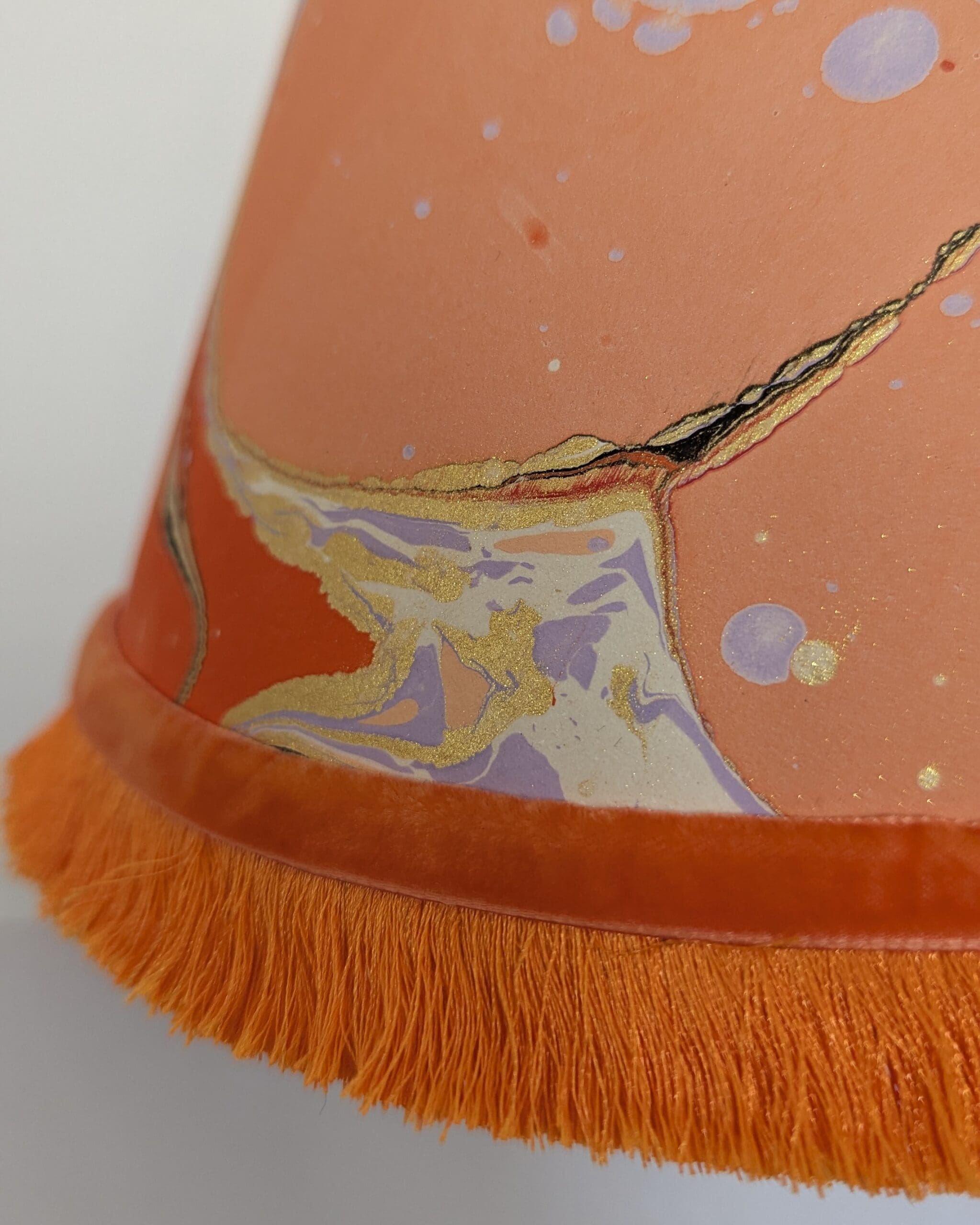 Peach marbled lampshade with bright orange trim and velvet ribbon