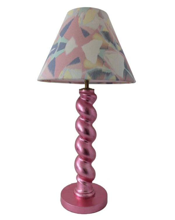 Cutout image of metallic pink twist table lamp with pastel geometric lampshade