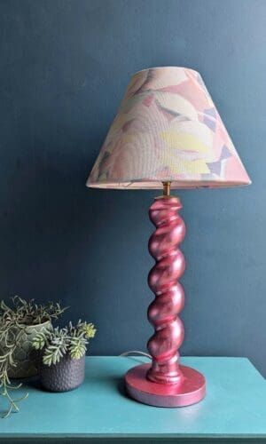 Metallic pink twist table lamp against a teal wall