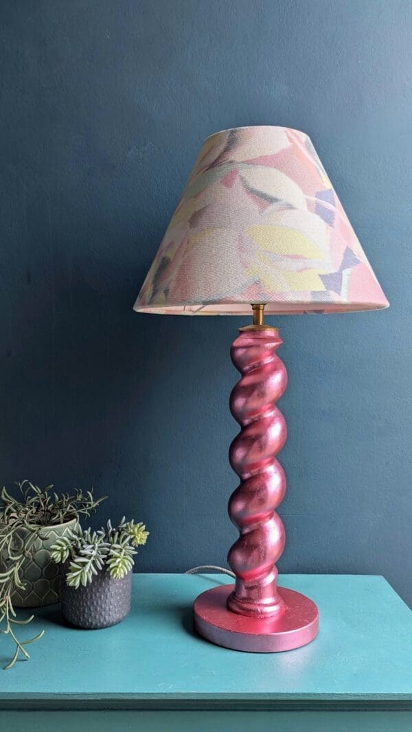 Metallic pink twist table lamp against a teal wall