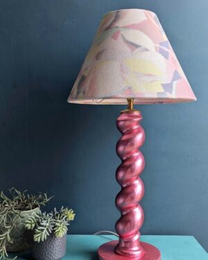 Metallic pink twist table lamp against a teal wall