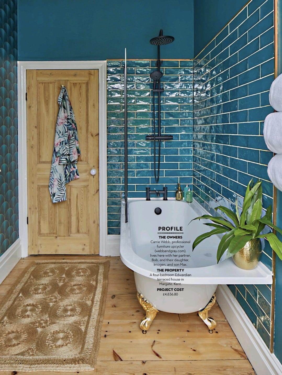 Bathroom with peacock blue tiles and wall, wood floor, jute rug and bath with gold feet