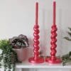 Large metallic red candlesticks on mantlepiece with plants