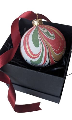 Red, green and gold marbled Christmas bauble with long red satin ribbon in black gift box