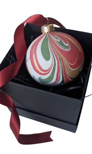Red, green and gold marbled Christmas bauble with long red satin ribbon in black gift box