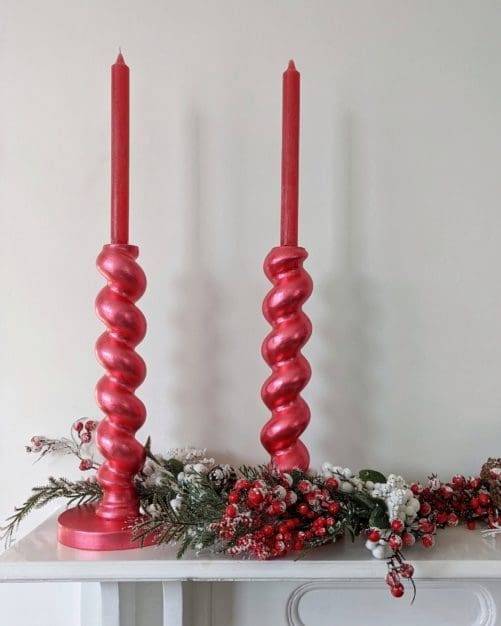 Metallic red chunky, barleytwist candlesticks on mantlepiece with snowy Christmas garland