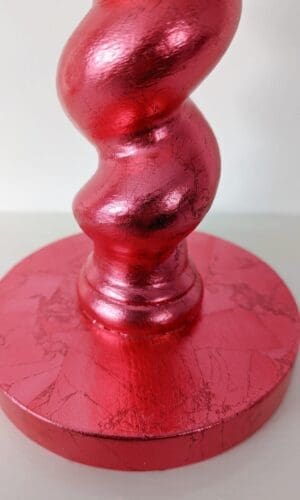 Close up of base of red candlestick showing soft metallic sheen and texture