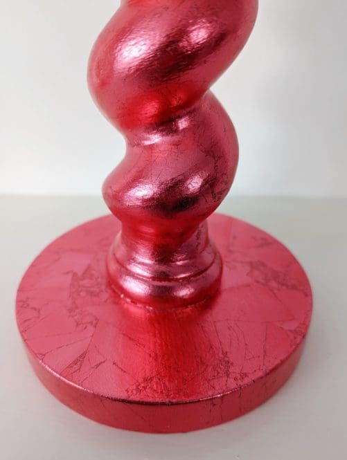 Close up of base of red gilded barleytwist candlestick showing soft metallic sheen and texture