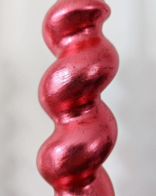 Close up of red gilded barleytwist candlesticks showing soft metallic sheen and texture